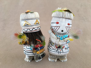 This set is a depiction of first man and woman. There is a lot going on in this set. The man wears a parrot feather Head pin with his eyes inlaid with gold lip mother of pearl. His teeth are zigzag with pipe stone and black jet pigment. Under his teeth is has a horse hair beard. Holding in his hand on the right is a bamboo with parrot feather prayer plume. Opposite hand holding more parrot feathers and a ladder of six corn representing the sacred directions. These are made of white shell, red spiny oyster s